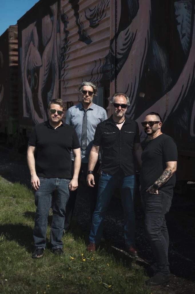 Boxcar Junction, four band members standing beside a mural-painted boxcar.