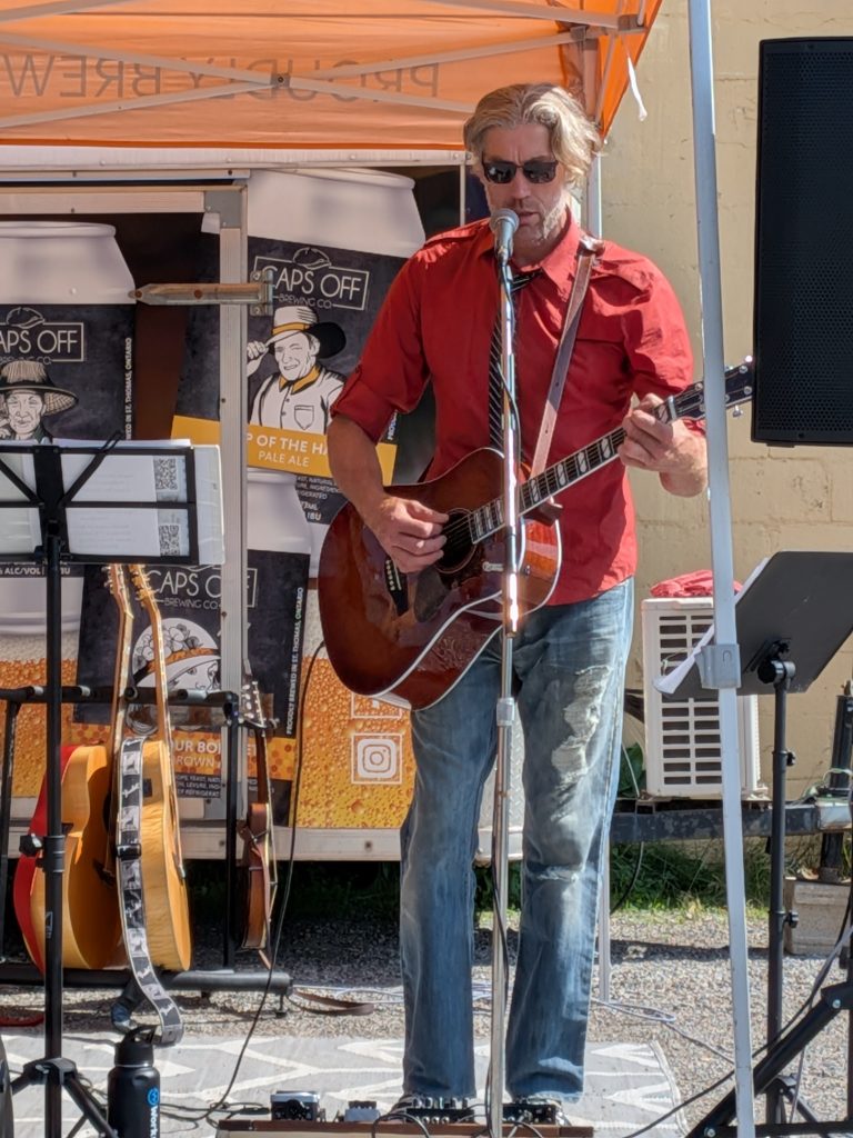 Jonathan, guitarist in Boxcar Junction, singing at a microphone while playing guitar.