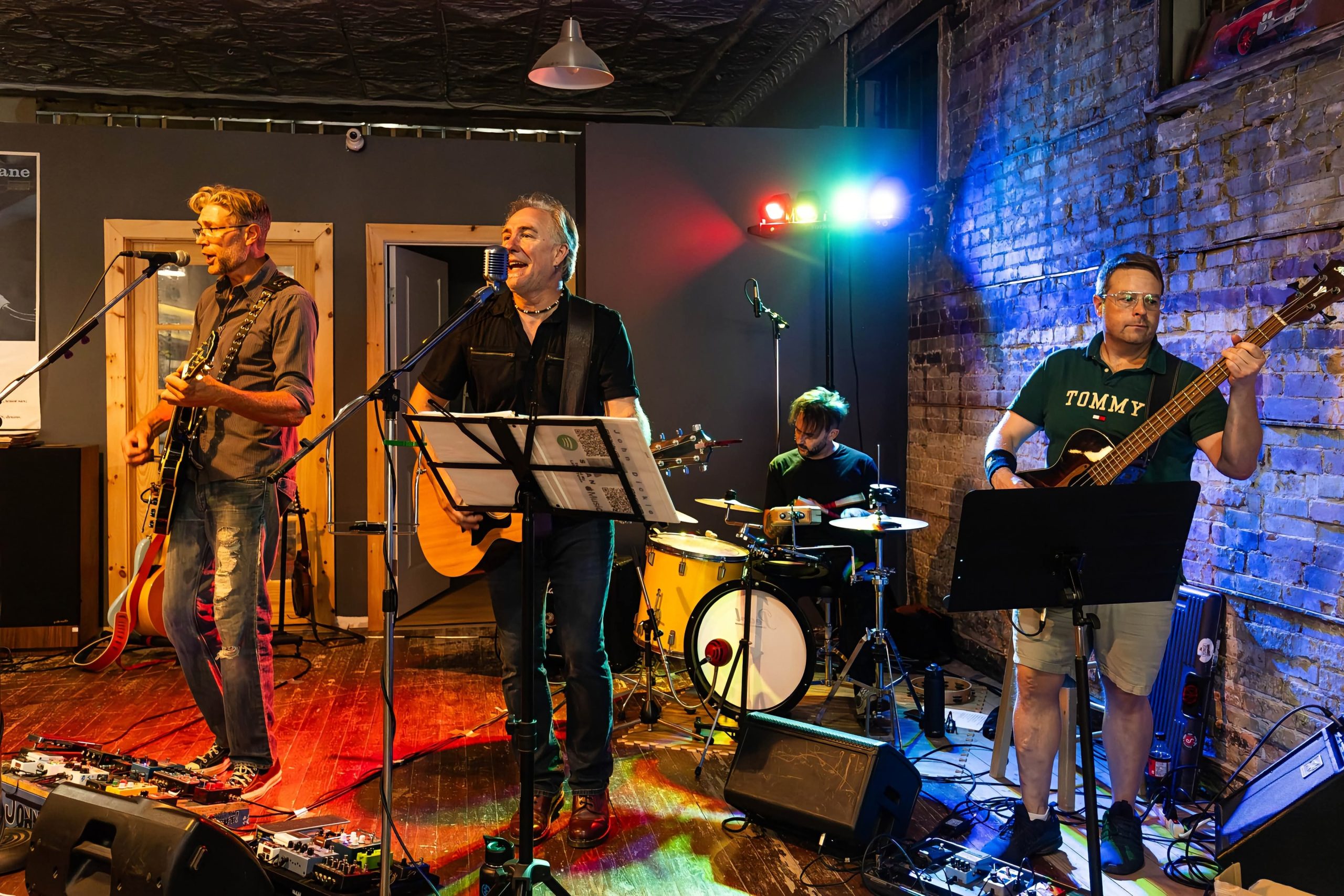 Boxcar Junction performing at Reed's Records in St. Thomas, with a blue-lit brick wall behind the band.